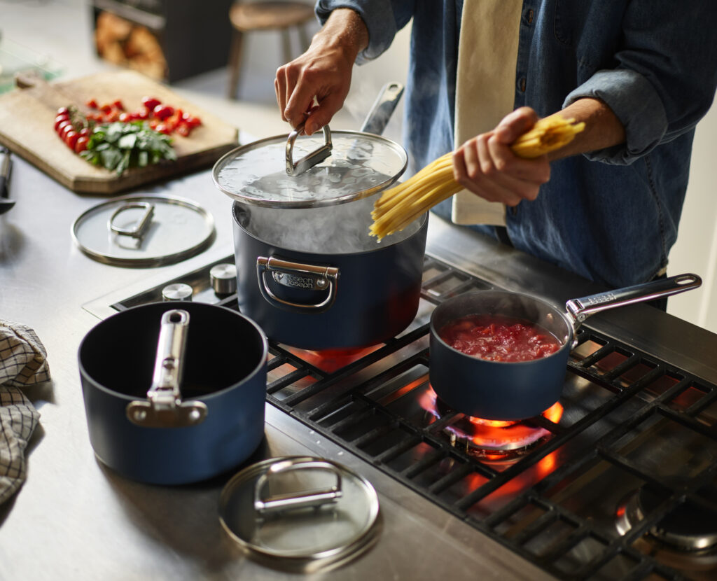 Space-saving cookware by Joseph Joseph with foldable handles neatly stacked in kitchen cabinet