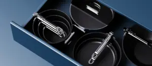 Space-saving cookware by Joseph Joseph with foldable handles neatly stacked in kitchen cabinet